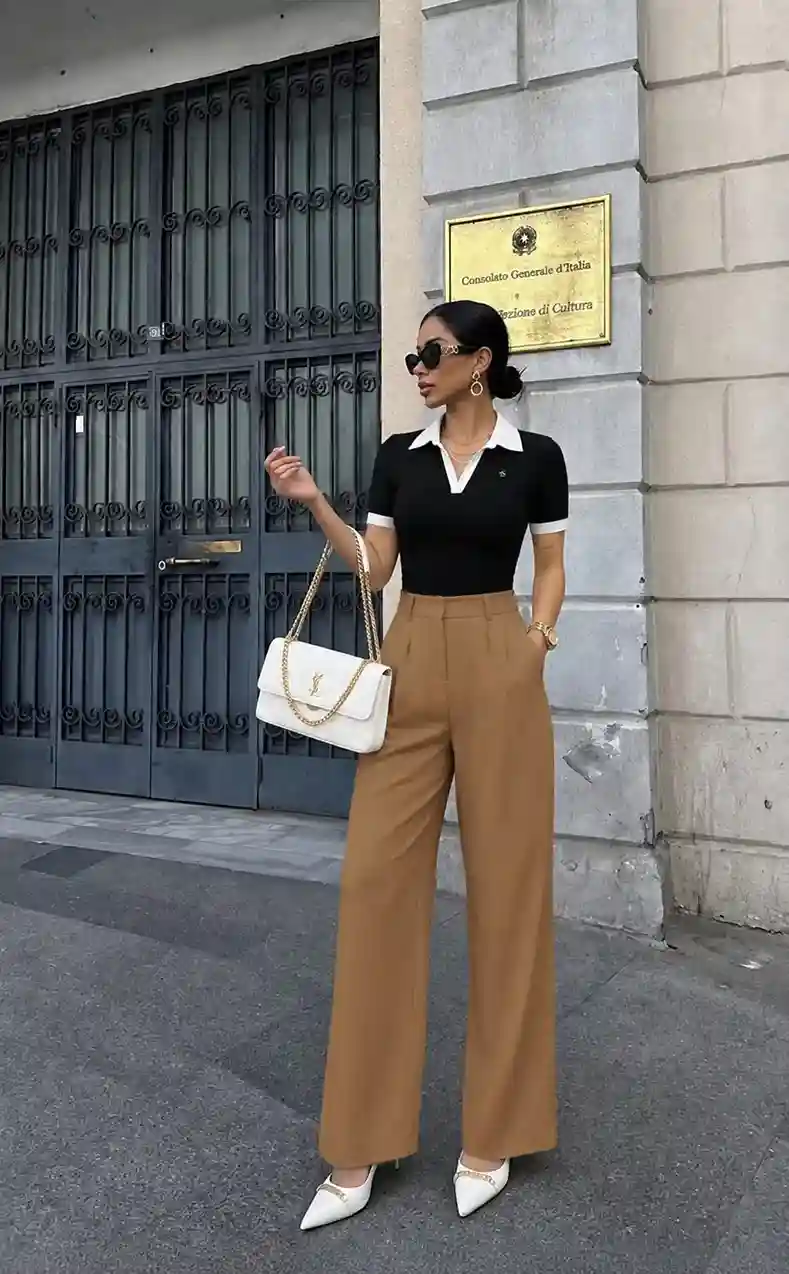 Woman styling camel wide leg dress trousers with a black knit polo top for a polished summer outfit.