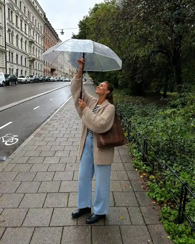 Woman wearing an oversized cardigan, barrel leg jeans, and waterproof Chelsea boots for a comfortable rainy day spring outfit.