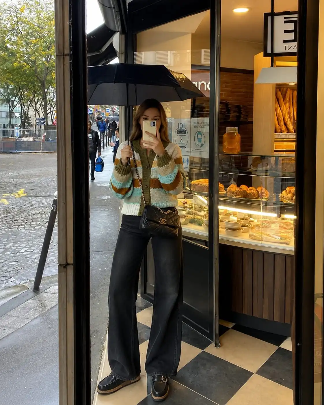 Woman wearing a striped knit cardigan, dark wash wide leg jeans, and water resistant clogs for wet spring weather.