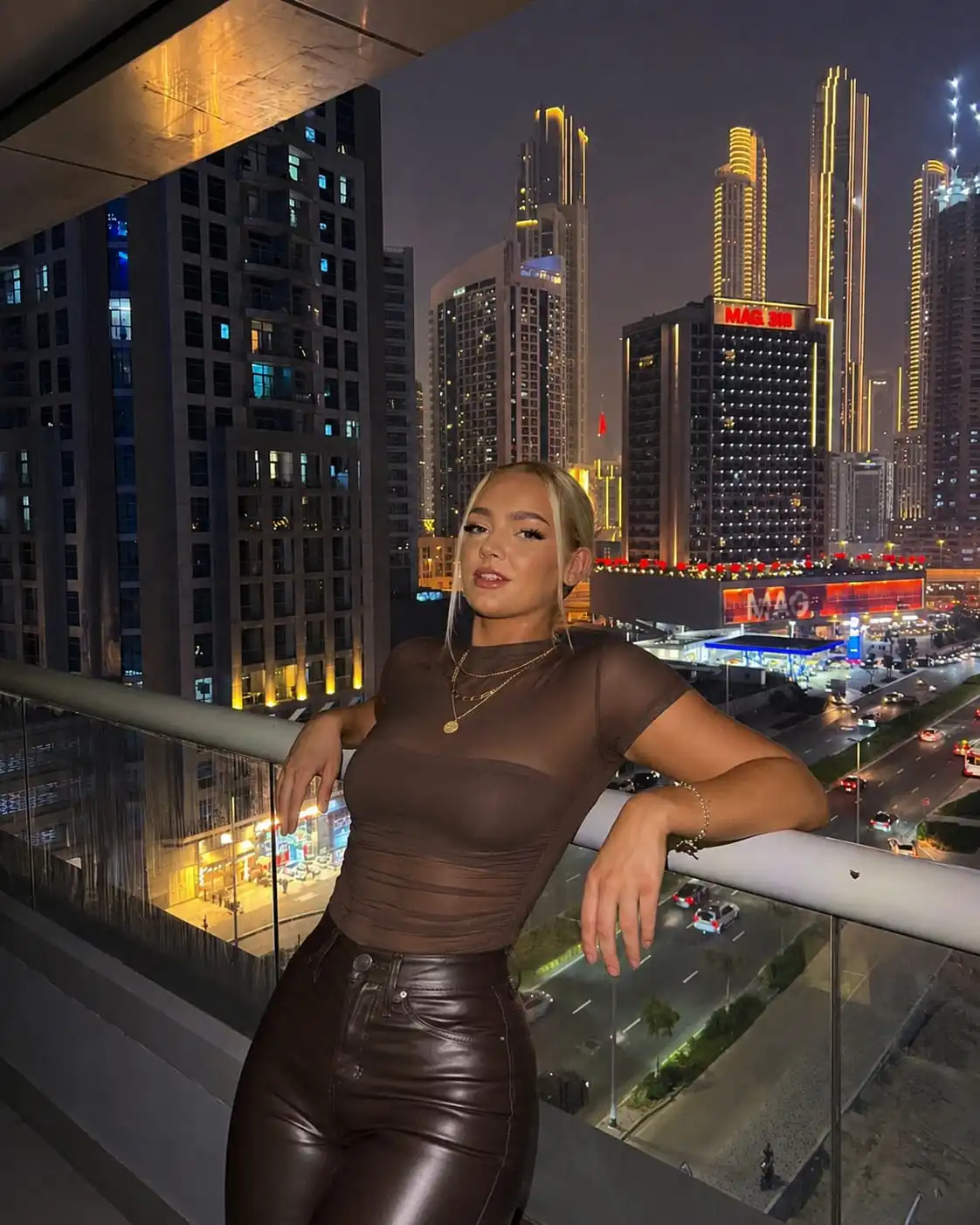 Woman wearing a mesh bodysuit and faux leather pants for trendy rooftop bar outfit ideas