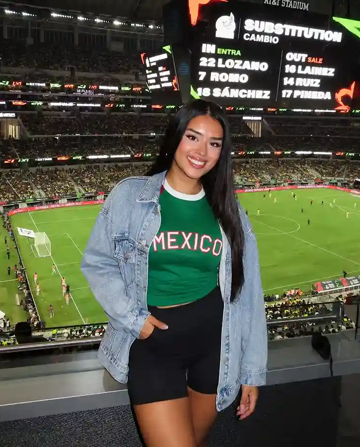Woman wearing a mexico game outfit featuring a green crop tee, black biker shorts, and an oversized denim jacket.