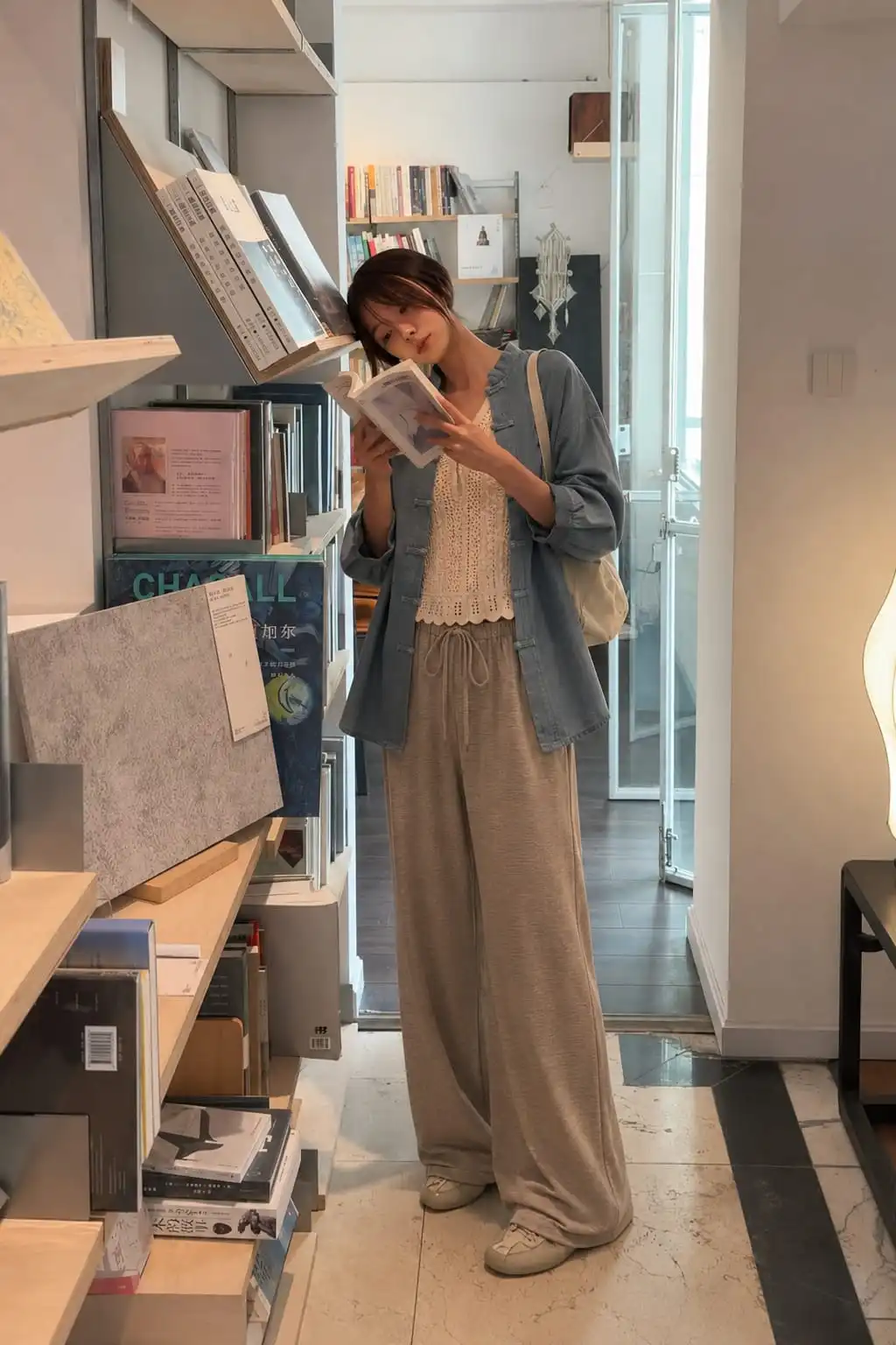 Woman wearing a lightweight blue jacket over a crochet tank top with wide-leg drawstring pants, perfect for cool summer evening outfit ideas.
