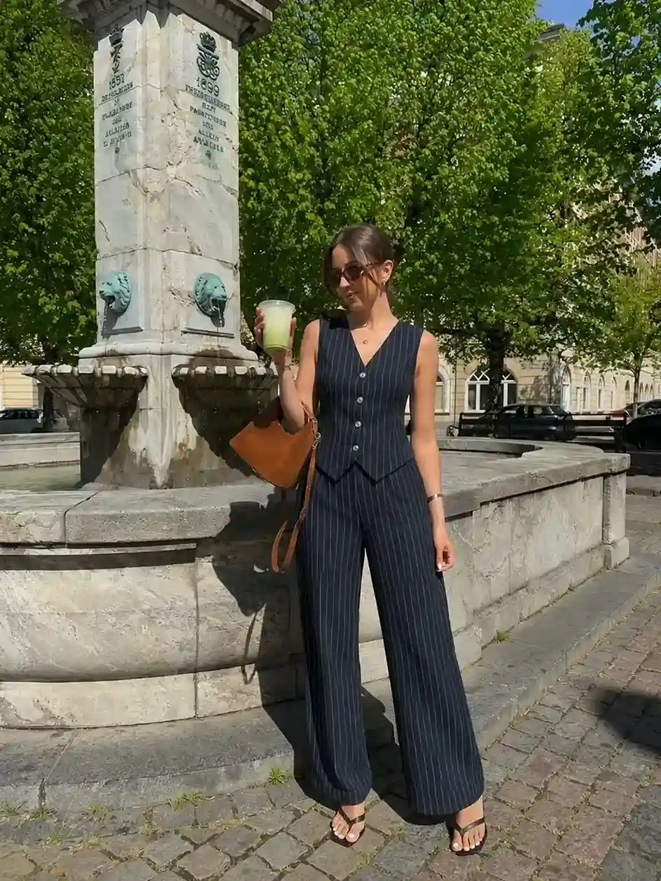 Black pinstripe vest and wide-leg trouser set styled with heeled sandals for a fashionable graduation guest outfit.