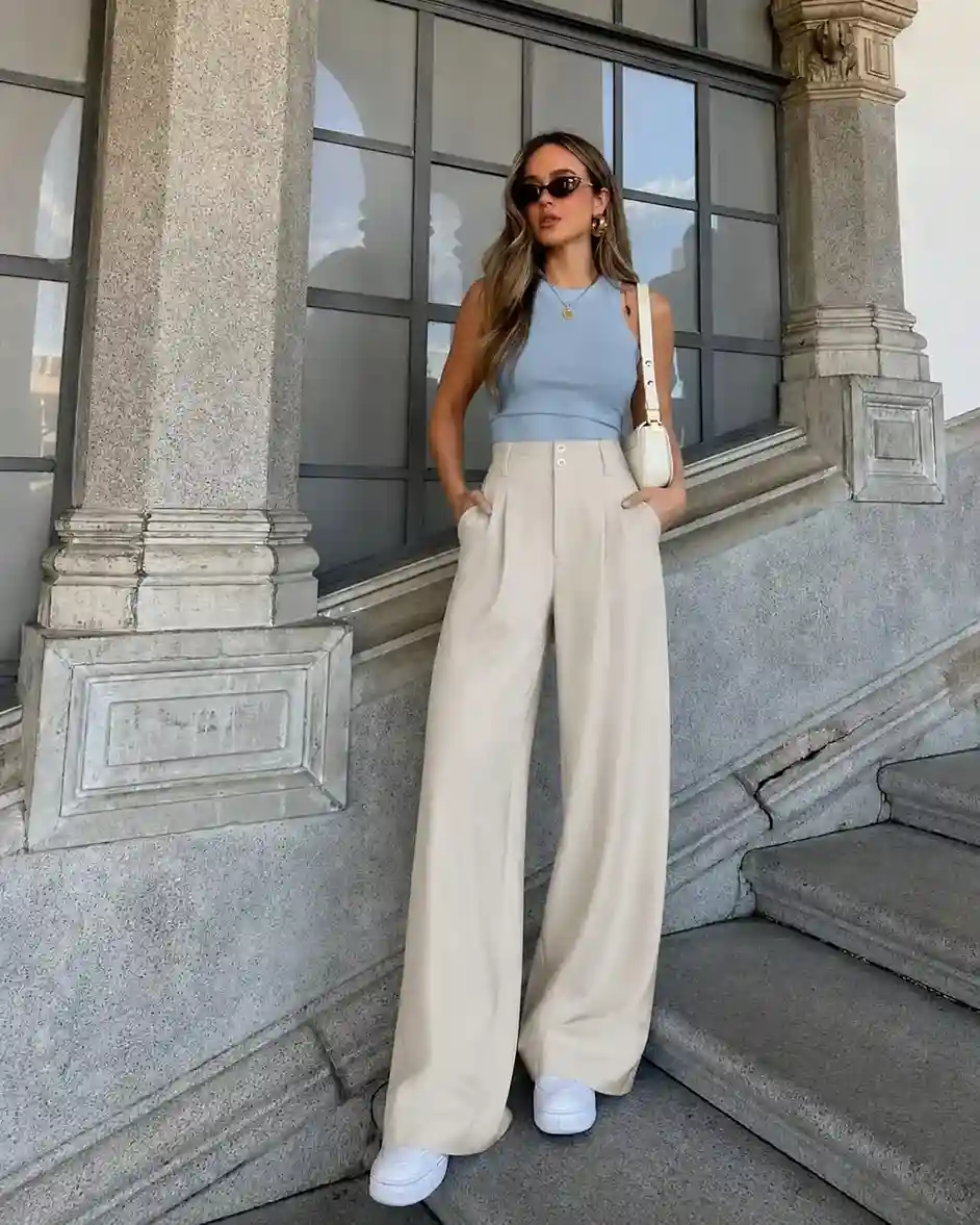 Woman wearing beige pleated wide leg trousers with a fitted black tank top for a classy summer wide leg trousers outfit.