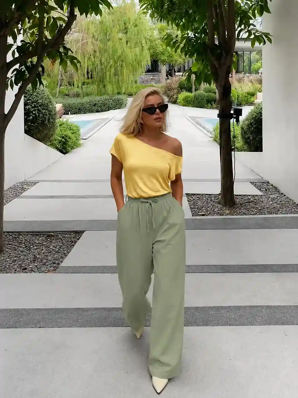 Woman wearing sage green wide leg trousers with a yellow off-the-shoulder top, creating a chic wide leg trousers outfit for summer.
