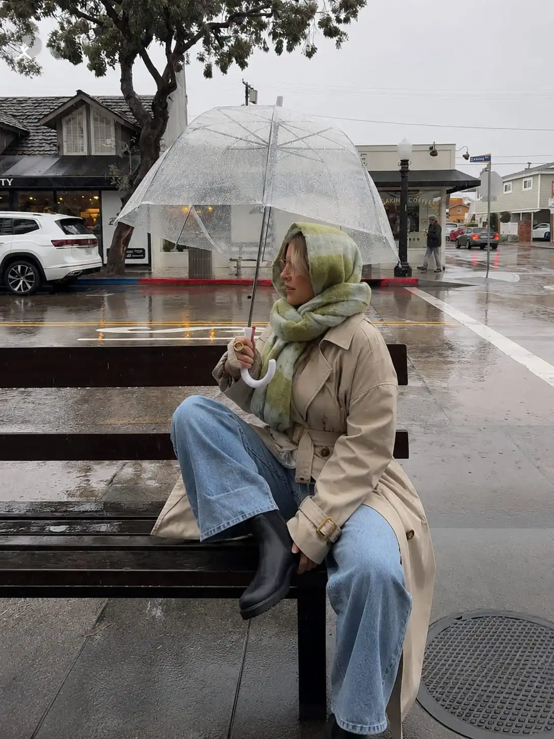 Woman styling a trench coat with wide leg jeans and waterproof Chelsea boots on a rainy spring day.