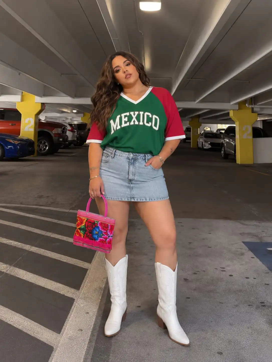 Woman wearing a western-inspired mexico game outfit with an oversized Mexico jersey, denim mini skirt, and white cowboy boots.