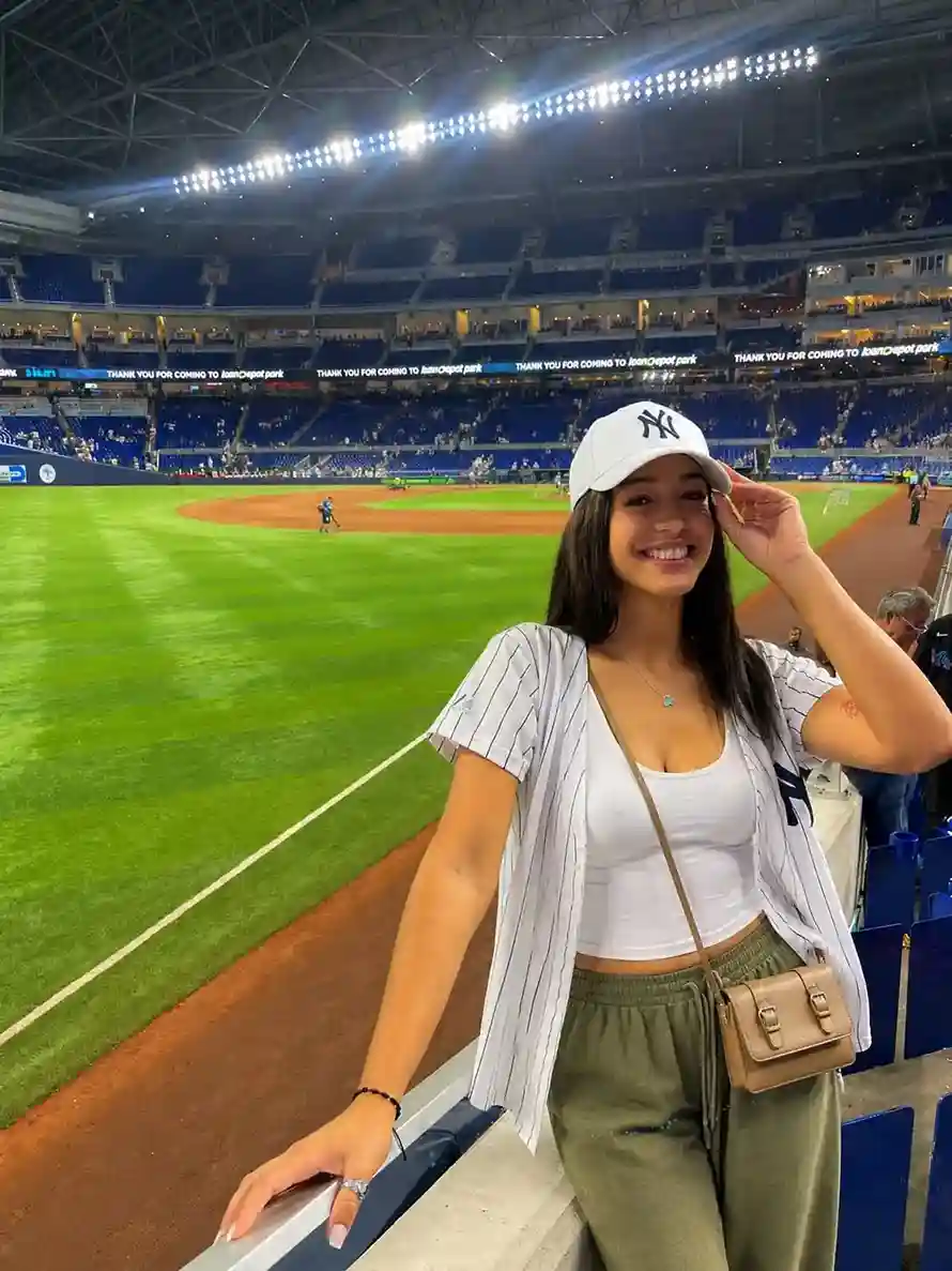 Woman styling a mexico game outfit with a white tank top, olive green wide-leg pants, and a crossbody bag for a stadium look.