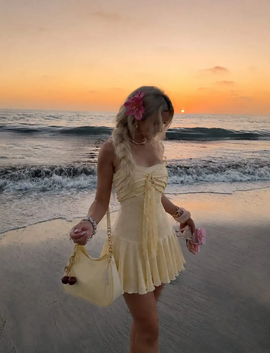 Woman wearing a yellow ruffle hem mini dress with a matching yellow shoulder bag for a bright beach vacation outfit for women.