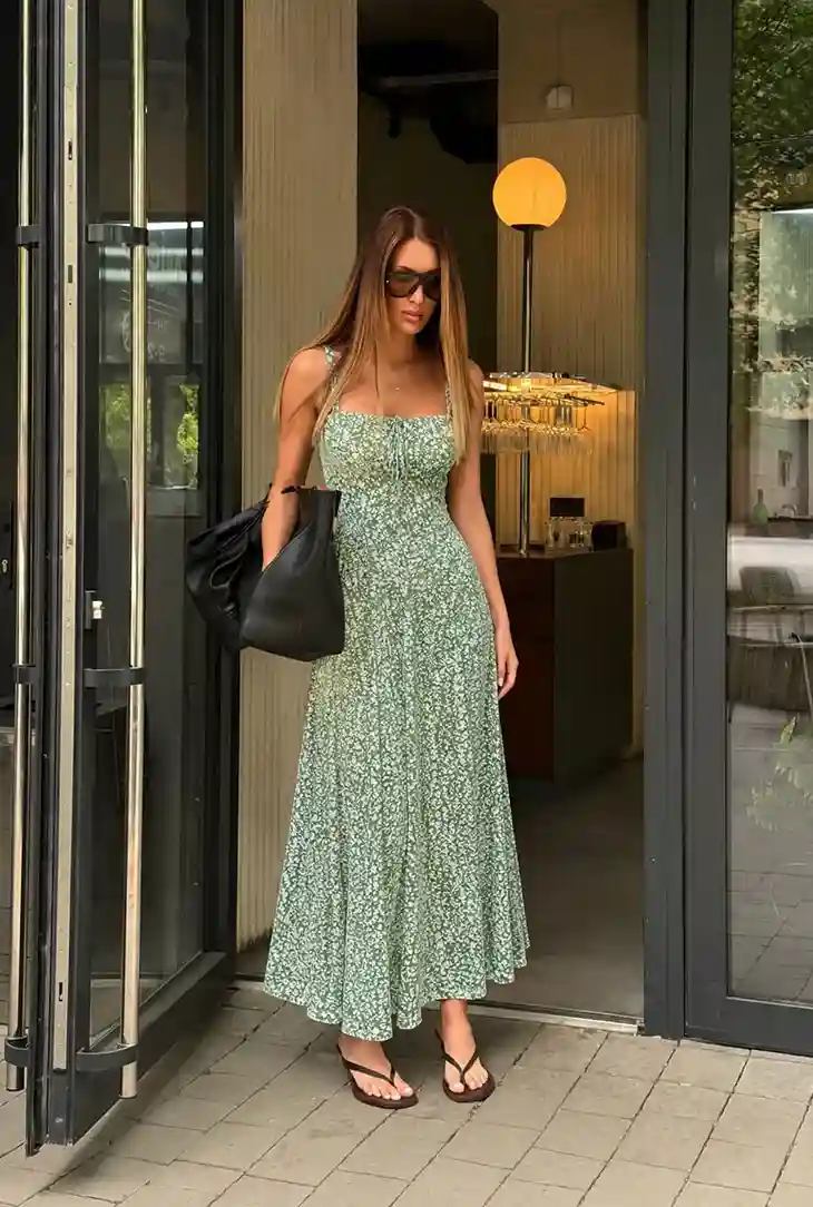 Woman wearing a green floral midi dress with a sophisticated summer look that shows how to dress classy on a budget.