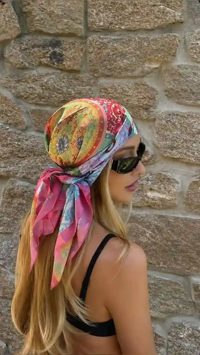 Woman wearing a multicolor glossy satin bandana tied as a stylish head scarf with sunglasses, featuring a silk-like Amazon bandana for summer outfits, vacations, and everyday fashion.