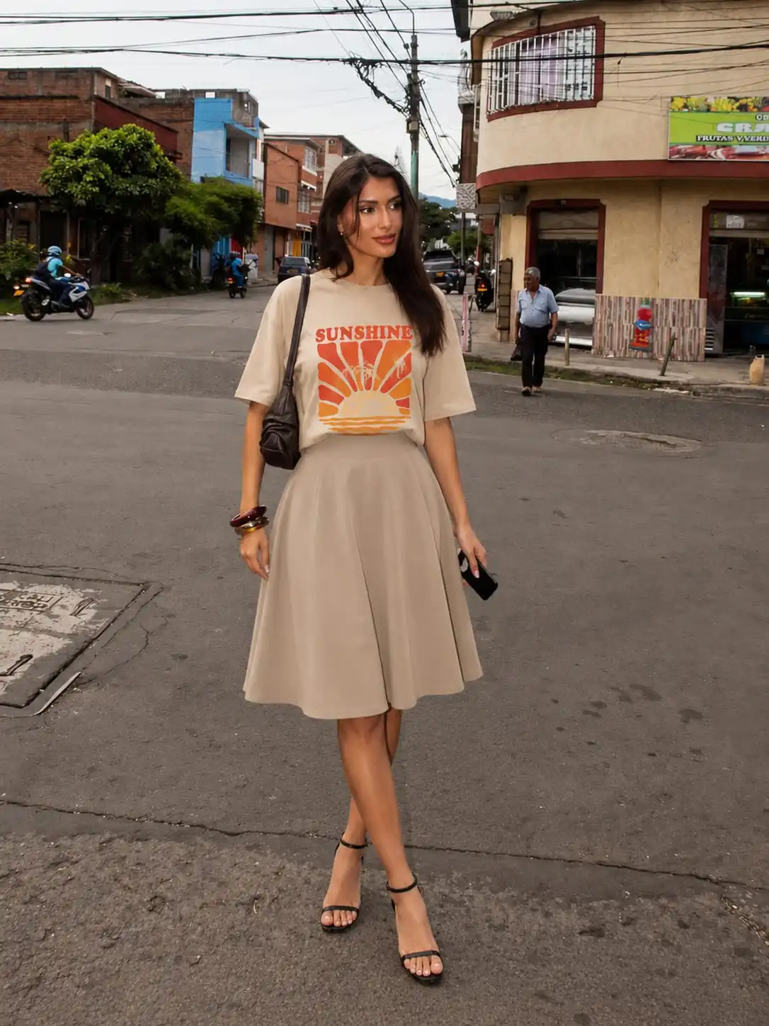 Woman wearing an oversized graphic T-shirt with a camel A-line midi skirt, showcasing a casual summer skirt outfit idea for everyday style.