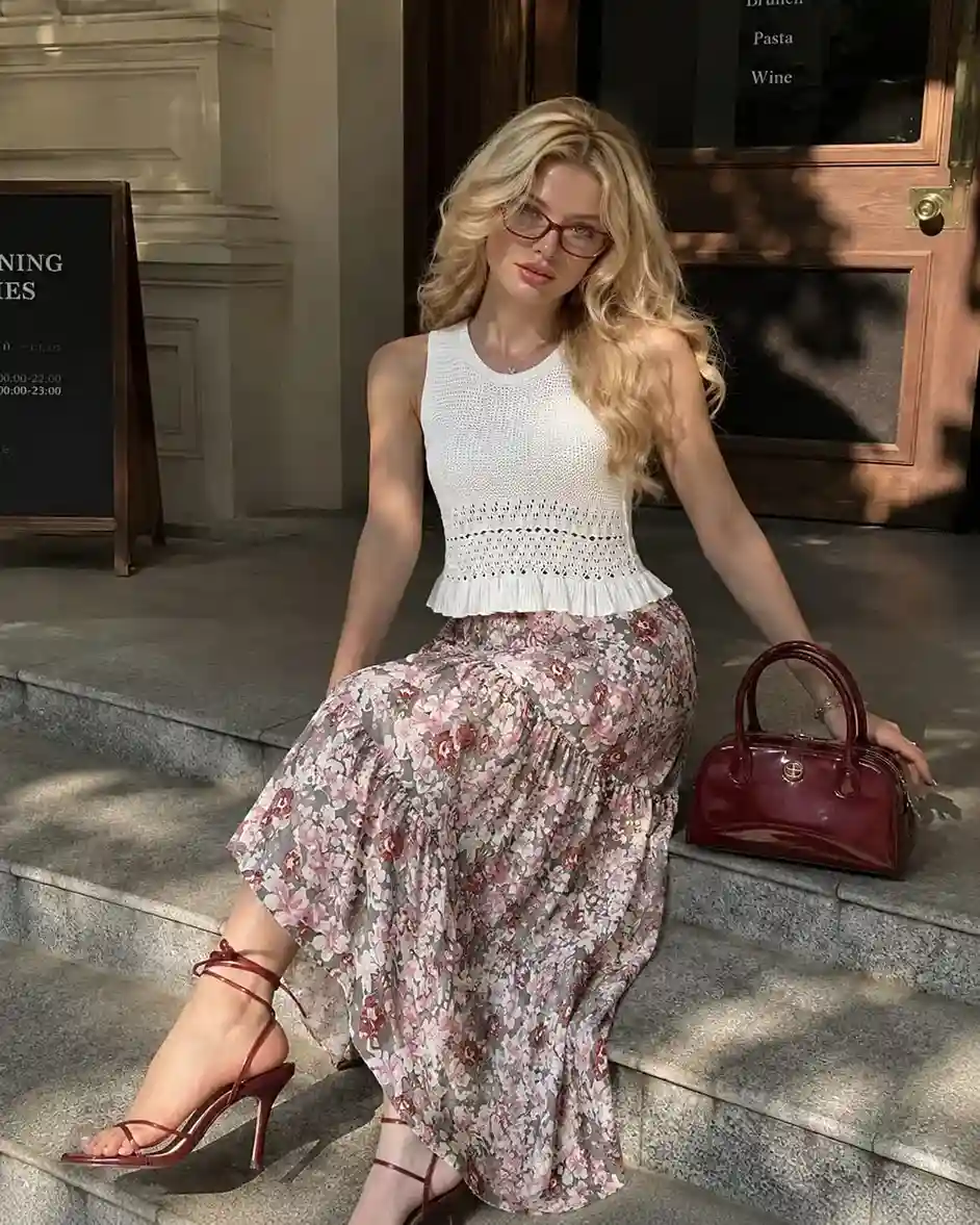 Woman wearing a white crochet knit tank top with a pink floral boho maxi skirt, showcasing a romantic summer skirt outfit idea for vacations and weekend brunches.